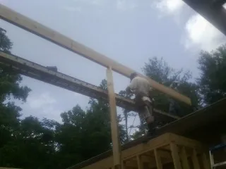 Carpenter setting a ridge beam over a new addition frame — Ice Dam Removal by Roofing Brothers in Rush Center