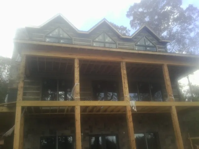 Dormers and porch framing on a large log home under construction — Roof Coating work by our crew in Rush Center