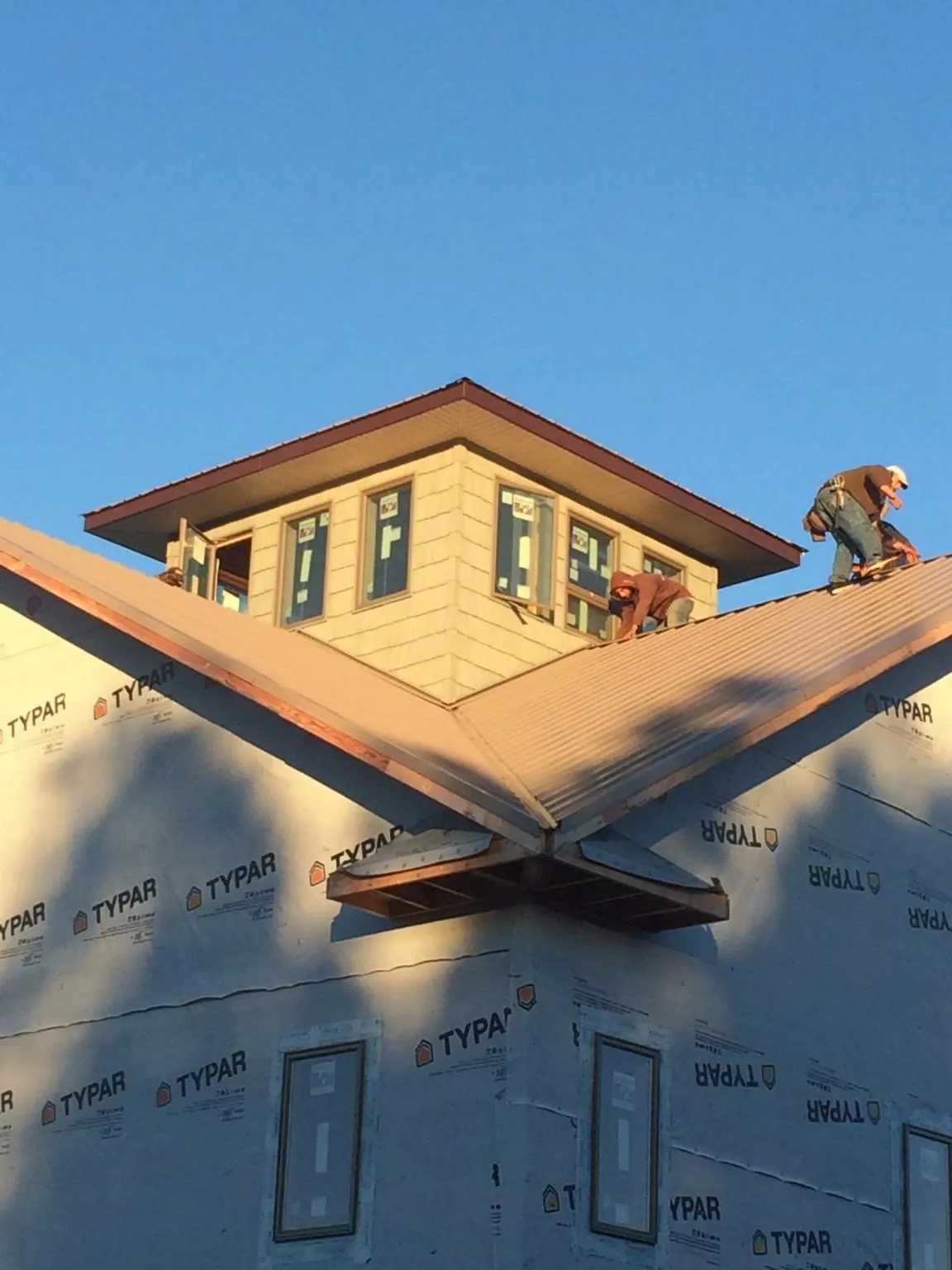 Roofers working around a rooftop cupola on a new metal roof at sunset — Roof Waterproofing in Rush Center by Roofing Brothers